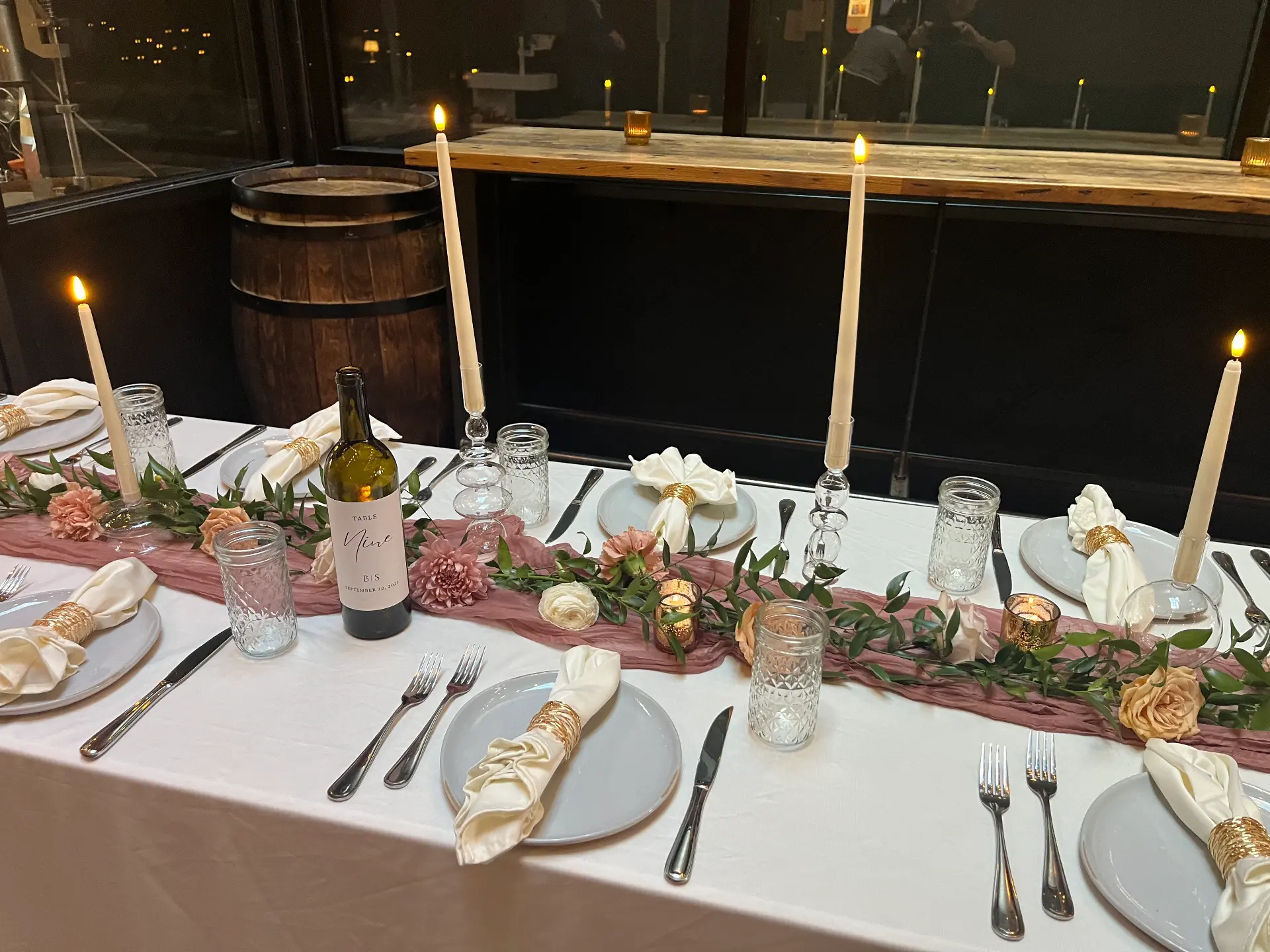 A candlelit head table with pink runners and greenery