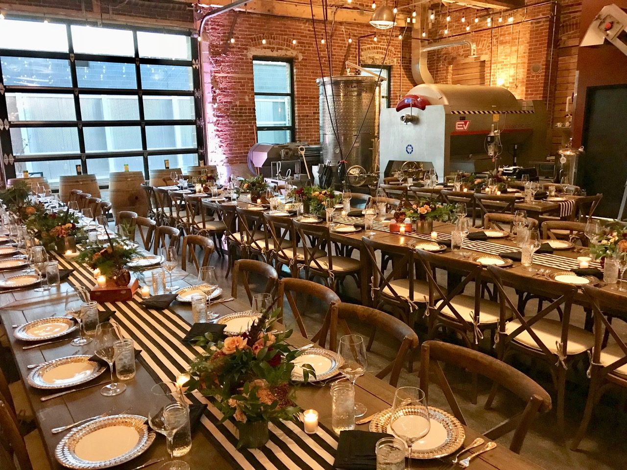 Farm tables set with florals and striped runners in the production hall