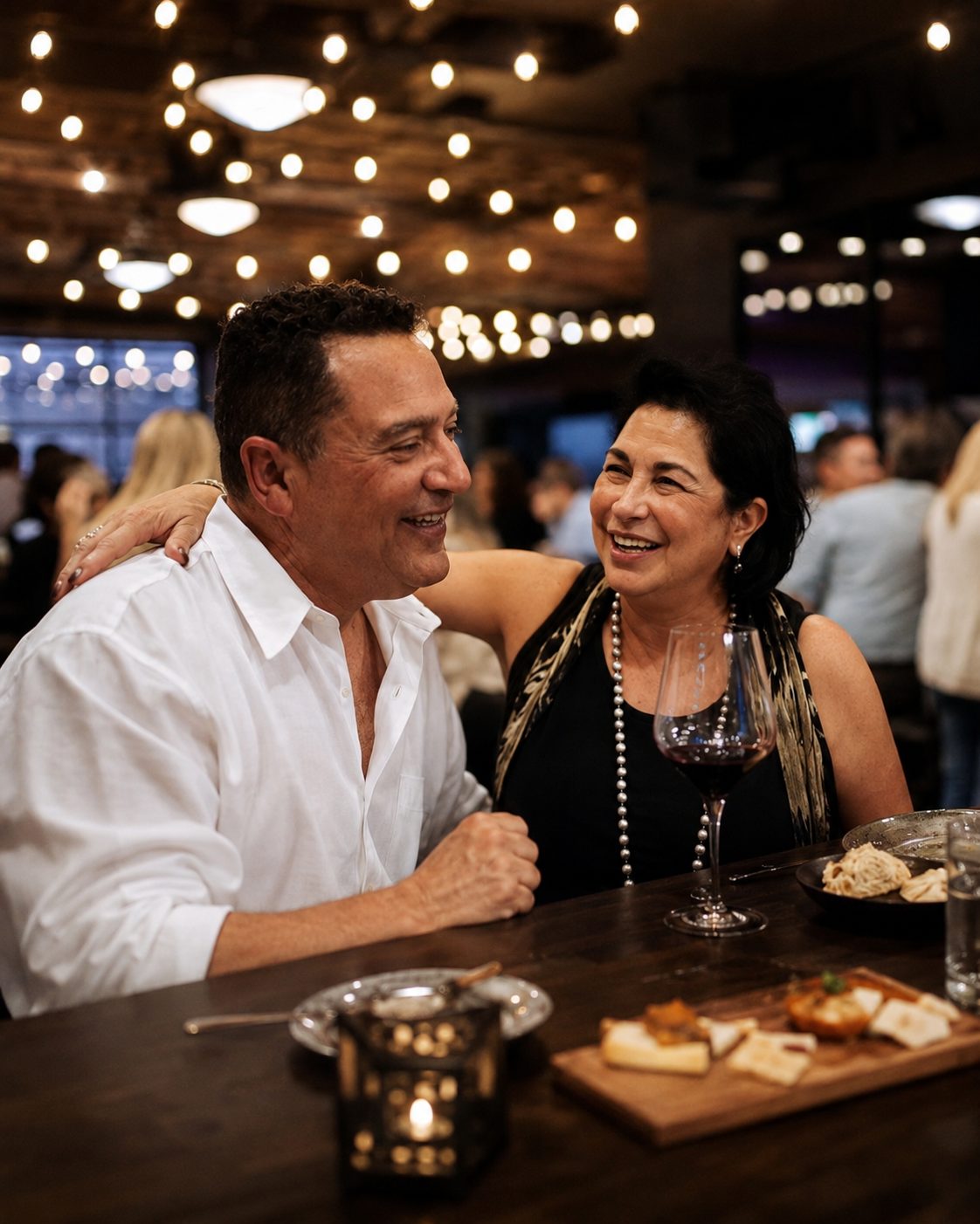 A couple laughing together over wine and cheese